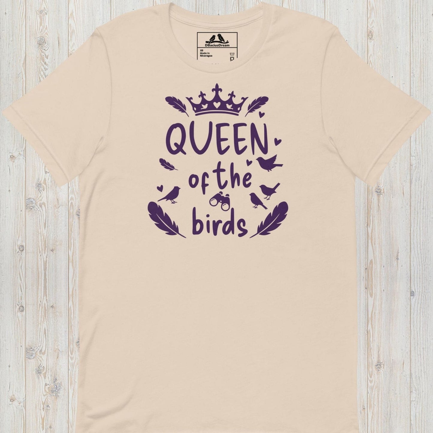 Light beige queen of the birds t-shirt with a purple bird graphic, crown design and decorative bird silhouettes